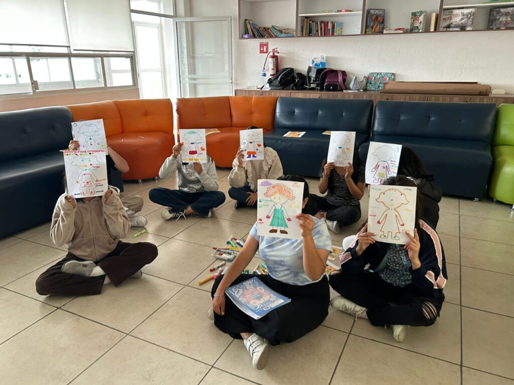 Niñas y niños trabajando en equipo en el aula, acompañados por docentes en un modelo de aprendizaje colaborativo.