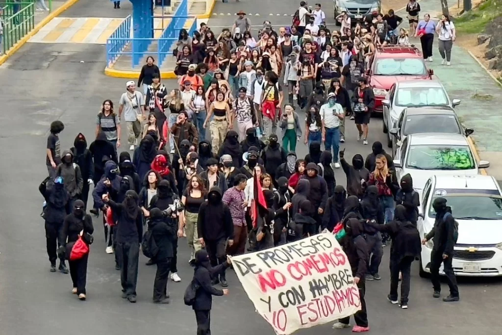 Estudiantes universitarios protestan frente a edificios institucionales, exigiendo democracia y participación en sus comunidades académicas.