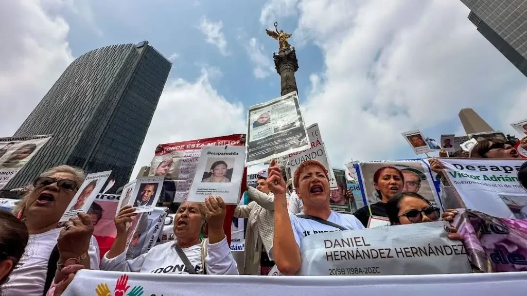 Madre con retrato de hijo desaparecido durante una jornada de búsqueda.