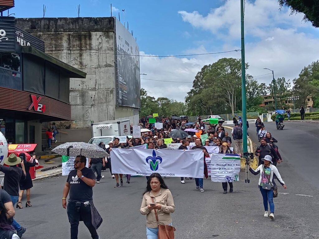 Ilustración de una universidad con de estudiantes y docentes en protesta al frente.